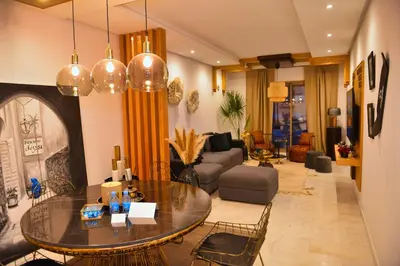 a living room with a table and a couch at Appartement de prestige climatisé à l'hivernage 400m de la Gare in Marrakech