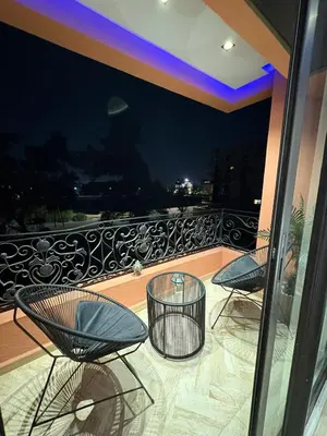 two chairs and two tables on a balcony at night at Hivernage - Stylish APT in the Heart of the City in Marrakech