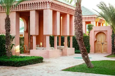 a pink building with palm trees in front of it at Amanjena Resort in Marrakech
