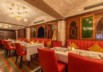 a dining room with tables and red chairs at Le Caspien Boutique Hotel in Marrakech