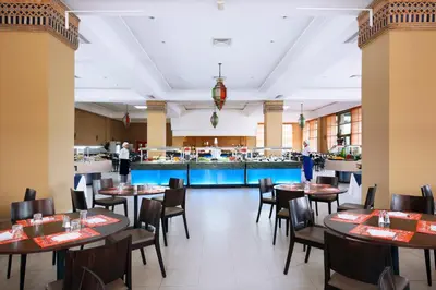 a dining room with tables and chairs and a kitchen at Valeria Dar Atlas All Inclusive in Marrakech