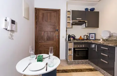 a kitchen with a white table with two wine glasses at Stylish Studio(WiFi, Netflix, Pool, AC, Nespresso) in Marrakech