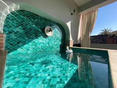 a pool with a blue tile floor and a swimming pool at Chimera Apartments & Suites in Marrakech