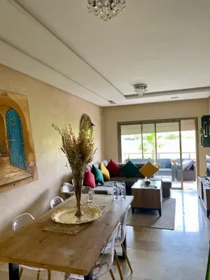 a living room with a table and a couch at Comme a la maison Prestigia Golf acces piscine in Marrakech
