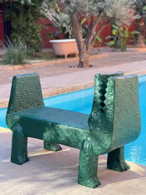 a green bench sitting in front of a pool at MORO Marrakech Boutique Hôtel in Marrakech
