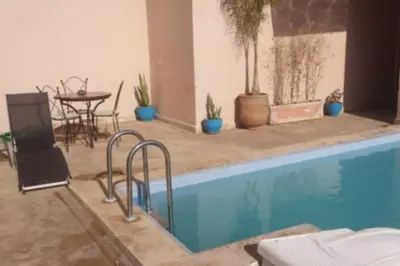 a swimming pool with a table and chairs and plants at Les terrasses de Gueliz in Marrakech
