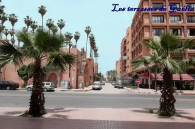 a city street with palm trees and a building at Les terrasses de Gueliz in Marrakech