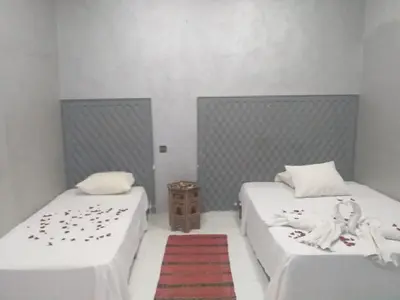 two beds in a room with a red rug at Hôtel Agnaou in Marrakech