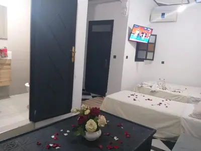 a room with a table with flowers and a tv at Hôtel Agnaou in Marrakech