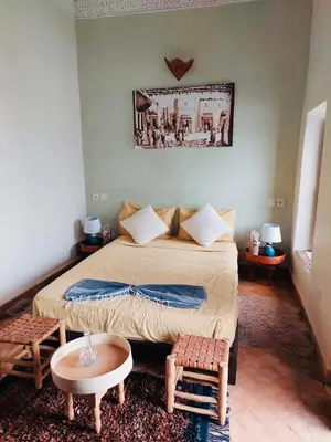 a bedroom with a large bed and two chairs at Riad Dialna in Marrakech