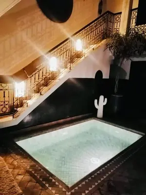 a pool in the middle of a room with a table at Riad Dialna in Marrakech