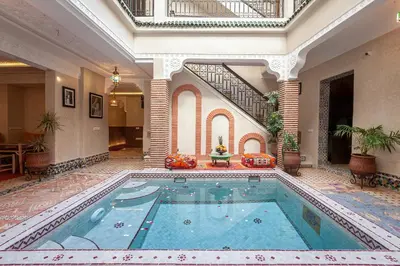 a large swimming pool in a large room with a building at Riad Salman in Marrakech