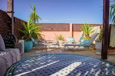 an outdoor patio with chairs and tables and potted plants at Riad zen&zin in Marrakech