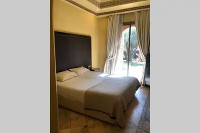 a bedroom with a bed and a large window at Bel appartement au Rez-de-jardin dans la palmeraie in Marrakech