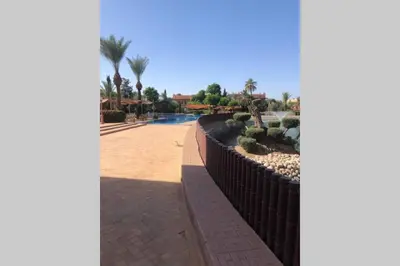 a fence with trees and cacti in a park at Bel appartement au Rez-de-jardin dans la palmeraie in Marrakech