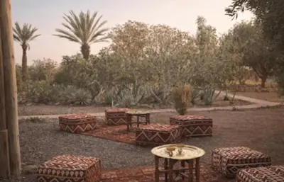 a group of tables and stools in a yard at Jnan Lotf Marrakech - Le Jardin de la Bienveillance in Marrakech