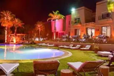 a swimming pool at night with chairs and a building at Villa Selma avec piscine chauffée in Marrakech