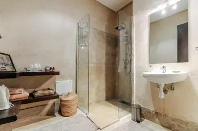 a bathroom with a glass shower and a sink at Villa ZITOUNA in Marrakech