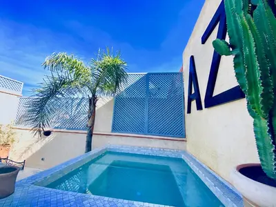 a swimming pool in front of a building with a cactus at AZ RIAD in Marrakech