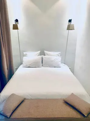 a bed with white sheets and pillows and two lamps at AZ RIAD in Marrakech
