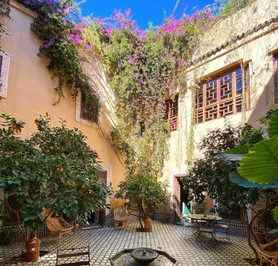 an outdoor courtyard with plants and tables and chairs at Riad KHOL Bohémia in Marrakech