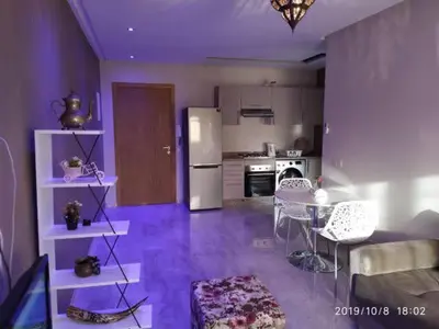 a living room with a kitchen with a table and a refrigerator at Superbe appartement Hivernage in Marrakech