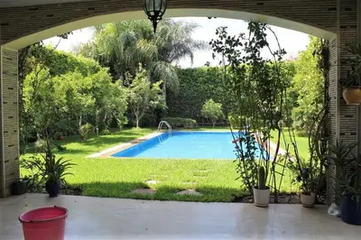 an archway leading to a swimming pool in a yard at Magnifique villa avec piscine chauffée que pour famille in Marrakech