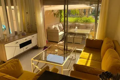 a living room with a couch and a glass table at Cosy Duplex, dans résidence avec piscine in Marrakech