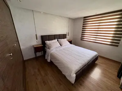 a bedroom with a large bed and a window at Cosy Duplex, dans résidence avec piscine in Marrakech