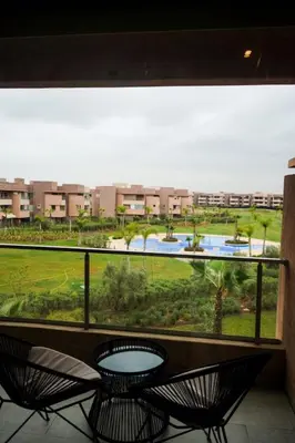 a balcony with two chairs and a view of a park at Prestigia Golf City Marrakech in Marrakech