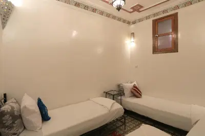 a white room with two beds and a window at Riad el Boukhiri in Marrakech