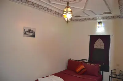 a living room with a red couch and a chandelier at Riad el Boukhiri in Marrakech