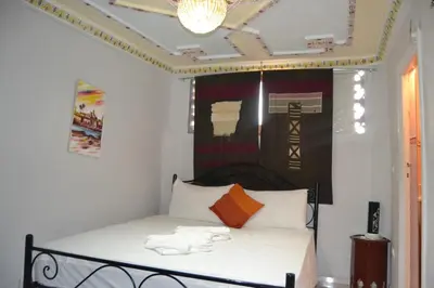 a bedroom with a bed with white sheets and a chandelier at Riad el Boukhiri in Marrakech