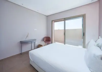 a white bedroom with a bed and a window at dar al walidine in Marrakech