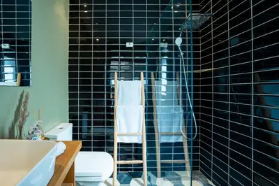 a black tiled bathroom with a shower and a toilet at dar al walidine in Marrakech