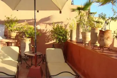 a balcony with chairs and an umbrella and potted plants at Emplacement N°1 ! RIAD ICA (EN EXCLUSIVITE) in Marrakech