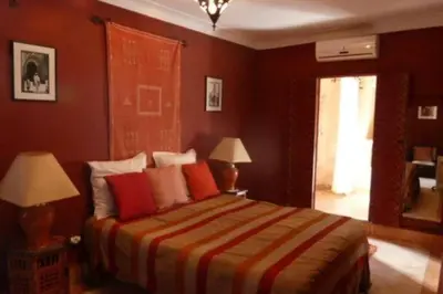 a bedroom with a bed with red walls and two lamps at Emplacement N°1 ! RIAD ICA (EN EXCLUSIVITE) in Marrakech