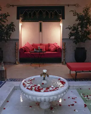 a living room with a red couch and a fountain at Riad Dar Habiba by Garden Wonders in Marrakech