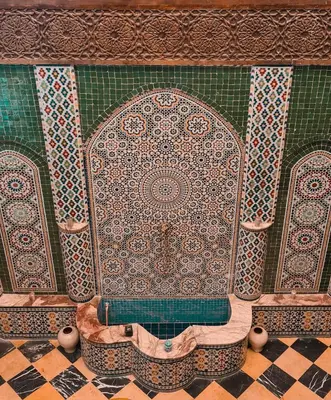 a bathroom with a tub with a tiled wall at Riad l'Escale de Marrakech in Marrakech