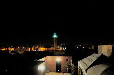 a clock tower with a green light on it at night at Riad l'Escale de Marrakech in Marrakech