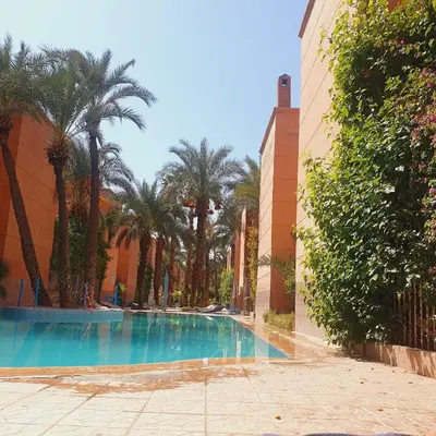 a swimming pool with palm trees next to a building at Chez Jasmeene in Marrakech