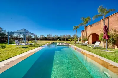 a swimming pool in a yard with palm trees at Villa Maloulou in Marrakech