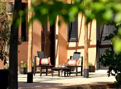 two chairs and a table in front of a building at Villa Dinari in Douar Caïd Layadi