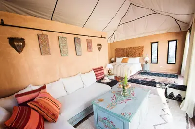 a living room with a couch and a bed in a tent at Villa Dinari in Douar Caïd Layadi