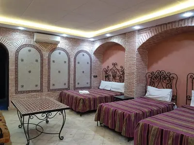 a hotel room with two beds and a table at Hotel Salsabil in Marrakech