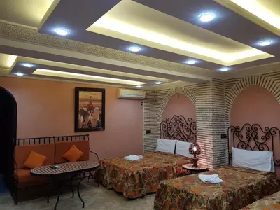 a hotel room with two beds and two tables at Hotel Salsabil in Marrakech