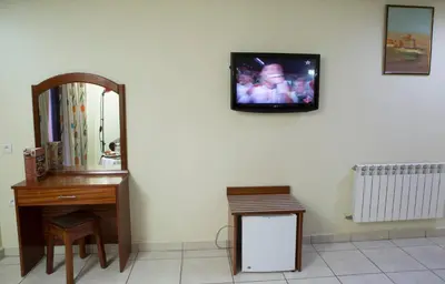 a room with a mirror and a vanity and a tv on a wall at Hotel Gomassine in Marrakech