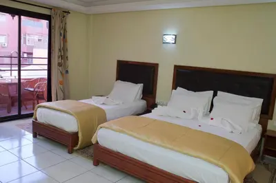 a hotel room with two beds and a balcony at Hotel Gomassine in Marrakech