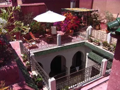 a balcony with an umbrella and chairs and flowers at Nadir Home in Marrakech