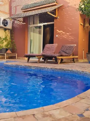 two chairs and a swimming pool in front of a house at Villa Lila in Marrakech